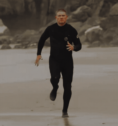 Man In Black Wetsuit Running On Beach GIF
