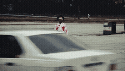 Man In Bloody Shirt Standing In Front Of Car GIF