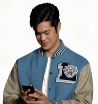 Man In Blue And Tan Varsity Jacket Looking At Cell Phone GIF