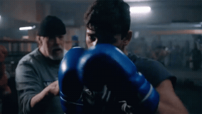 Man In Blue Boxing Gloves Being Instructed In Gym GIF