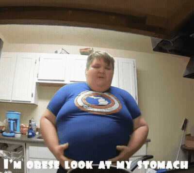 Man In Blue Captain America Shirt Holding Belly In Kitchen GIF