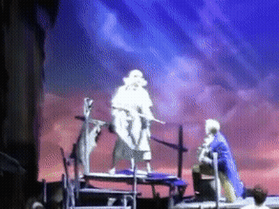 Man In Blue Coat Standing On Stage With Sword GIF