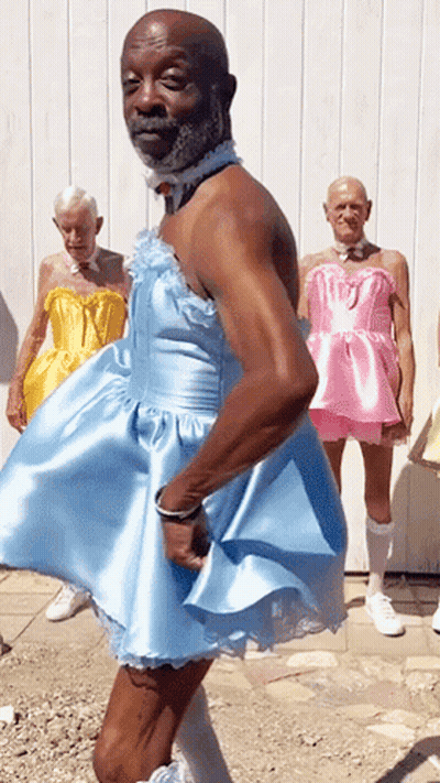 Man In Blue Dress With Men In Pink Dresses GIF