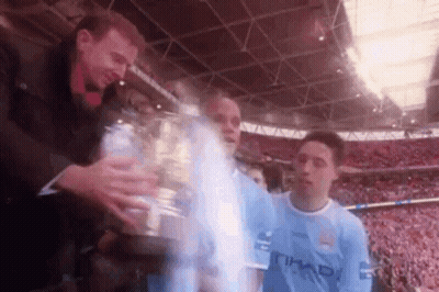 Man In Blue Etihad Shirt Holding Trophy GIF
