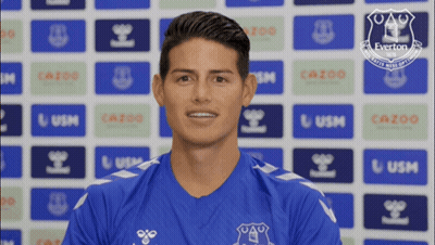 Man In Blue Everton Shirt Smiling In Front Of Everton Logos GIF