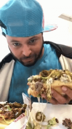 Man In Blue Hat And Blue Shirt Eating Hamburger GIF