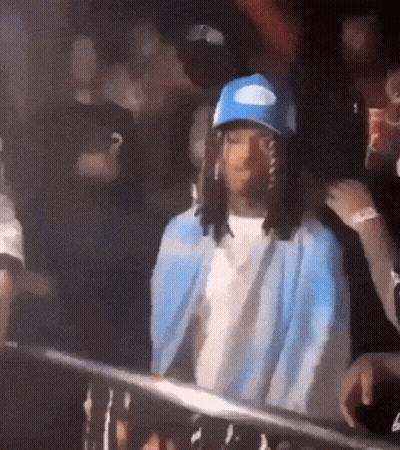 Man In Blue Hat And Jacket Standing In Crowd GIF