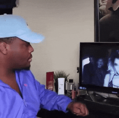 Man In Blue Hat And Purple Jacket Watching TV GIF