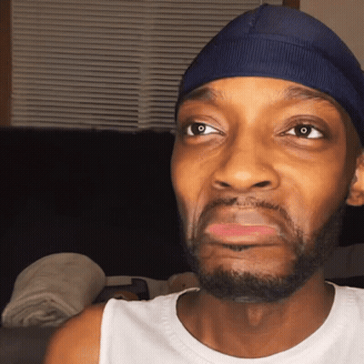 Man In Blue Hat And White Tank Top Looking At Camera GIF
