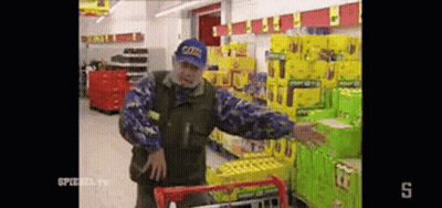 Man In Blue Hat Pushing Shopping Cart GIF