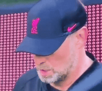Man In Blue Hat With Pink Logo Looking Down GIF