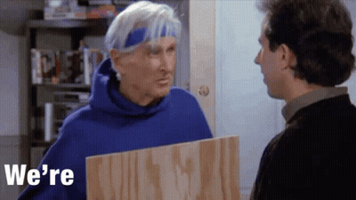 Man In Blue Hoodie Holding Board Talking To Another Man GIF
