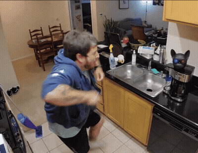 Man In Blue Hoodie In Kitchen By Sink And Coffee Maker GIF