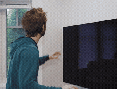 Man In Blue Hoodie Standing In Front Of TV GIF
