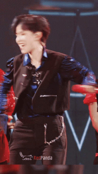 Man In Blue Jacket And Black Pants Dancing In Front Of Redpanda Sign GIF