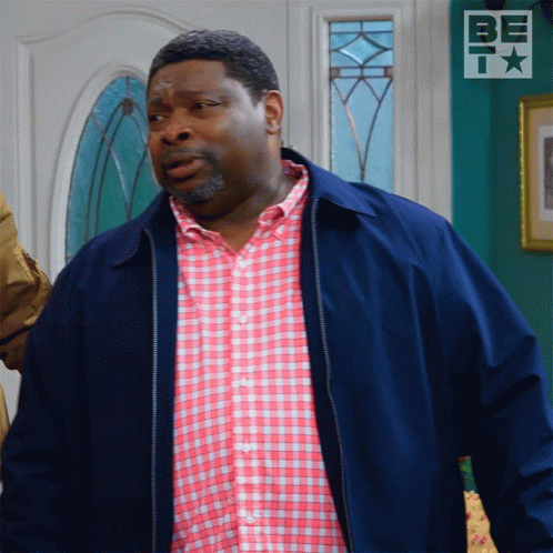 Man In Blue Jacket And Pink Plaid Shirt At Bet Sign GIF