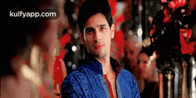 Man In Blue Jacket And Red Tie In Front Of Red Wall GIF