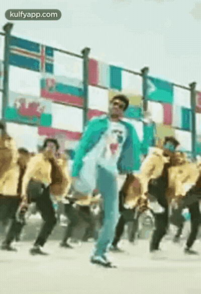 Man In Blue Jacket Dancing By Fence With Flags GIF