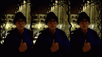 Man In Blue Jacket Giving Thumbs Up In Front Of Building GIF