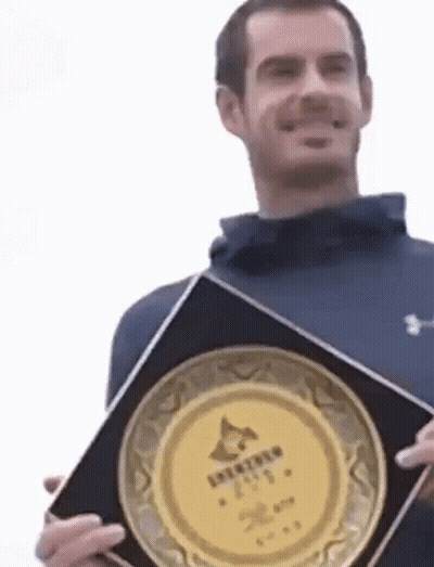 Man In Blue Jacket Holding Plaque GIF