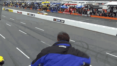 Man In Blue Jacket On Race Track With NASCAR.com Sign GIF