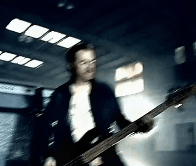 Man In Blue Jacket Playing Bass Guitar In Dark Room GIF