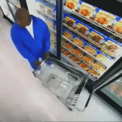 Man In Blue Jacket Pushing Shopping Cart In Front Of Refrigerator GIF