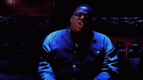 Man In Blue Jacket Singing Into Microphone In Dark Room GIF