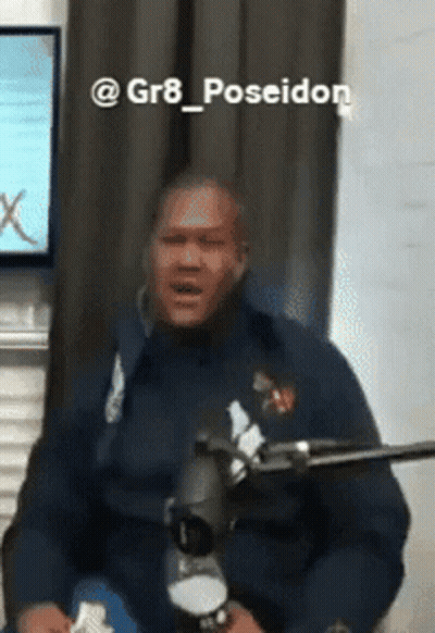 Man In Blue Jacket Sitting At Microphone Poseidon GIF