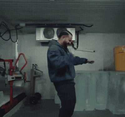 Man In Blue Jacket Squatting With Yellow Bucket GIF