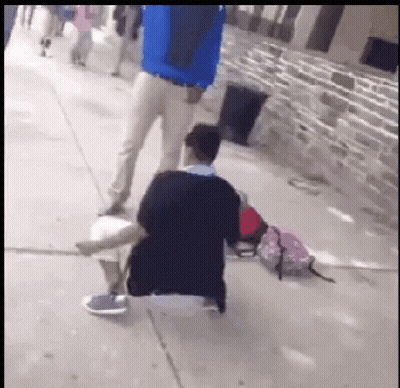 Man In Blue Jacket Standing Beside Kneeling Man GIF
