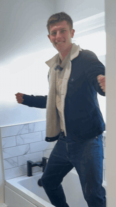Man In Blue Jacket Standing In Front Of Bathtub GIF