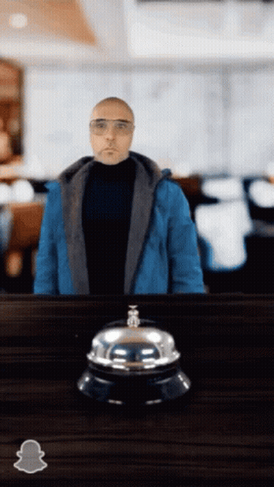 Man In Blue Jacket Standing Next To Bell GIF