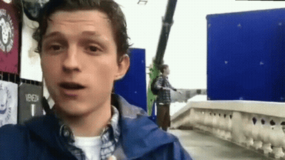Man In Blue Jacket Standing On Bridge Talking GIF