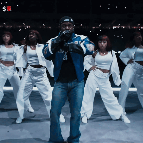 Man In Blue Jacket Surrounded By Female Dancers GIF