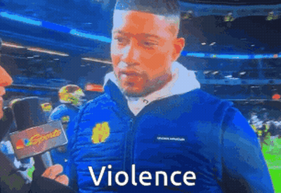 Man In Blue Jacket Talking Into Microphone With Violence GIF