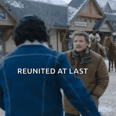 Man In Blue Jacket Talking To Man In Brown Jacket In Snowy Town GIF