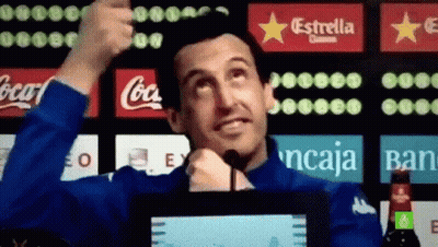 Man In Blue Jacket Thumbs Up In Front Of Coca Cola And Estrella Ads GIF