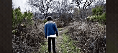 Man In Blue Jacket Walking Down Dirt Path In Woods GIF