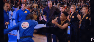 Man In Blue Jacket With Karate On Back Kicking Another Man GIF