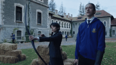 Man In Blue Jacket With M Next To Woman With Bow And Arrow GIF