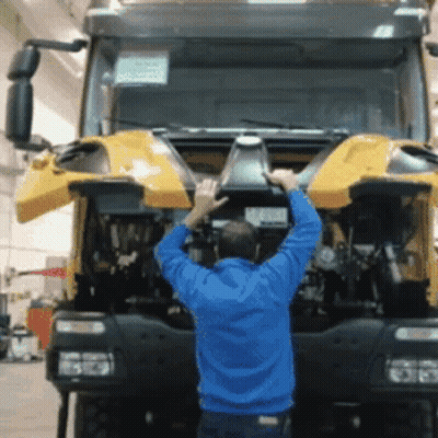 Man In Blue Jacket Working On Truck With Hood Open GIF