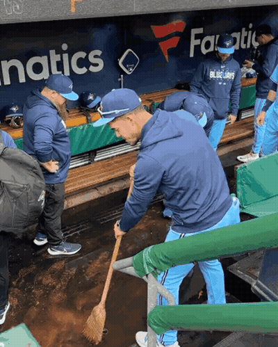 Man In Blue Jays Sweatshirt Sweeping Dirt In Dugout GIF
