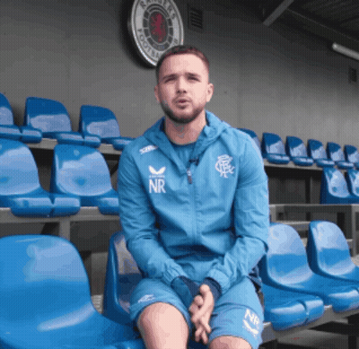Man In Blue NR Jacket Sitting In Blue Chairs GIF