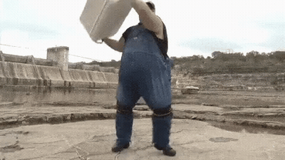 Man In Blue Overalls Holding White Bucket Over Head By Water GIF