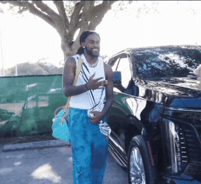 Man In Blue Pants And White Tank Top Standing By Black Car GIF