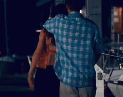 Man In Blue Plaid Shirt Hugging Woman In Dark Room GIF