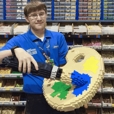 Man In Blue Power Model Builder Shirt Holding Lego Palette GIF
