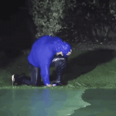 Man In Blue Raincoat Kneeling In Grass GIF