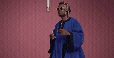 Man In Blue Robe At Microphone On Pink Background GIF